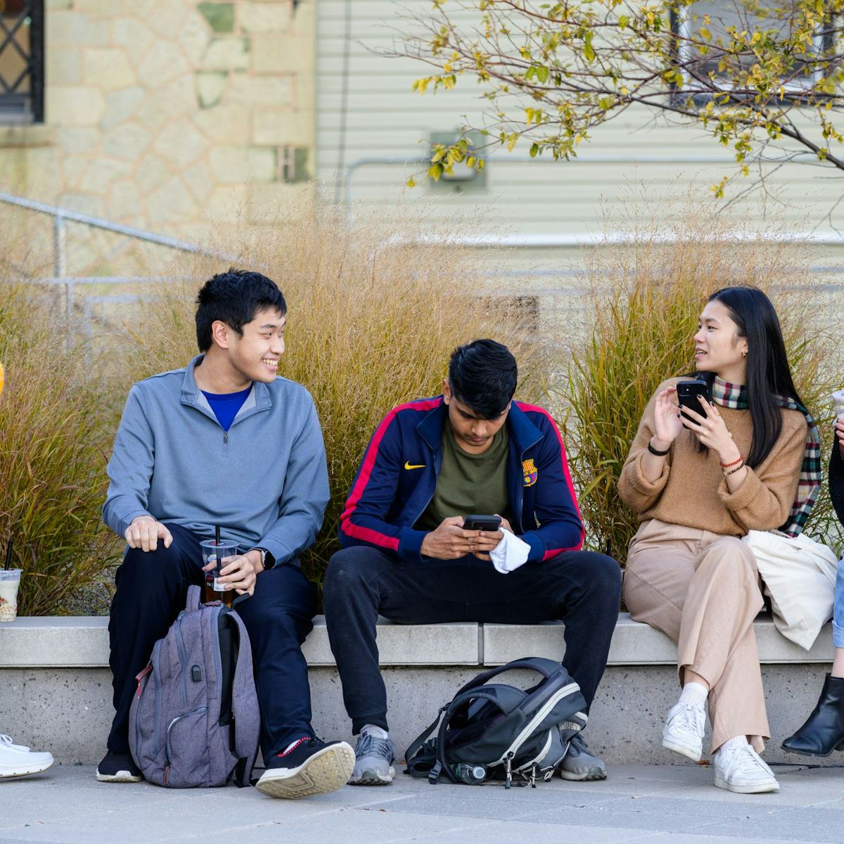 Group of students having a conversation on a bench outside Babbio Center.